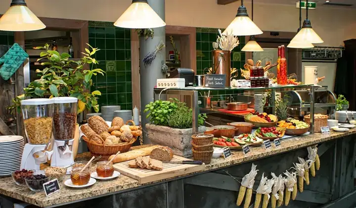 Reich gedecktes Frühstücksbuffet mit Broten, Gebäck, Aufschnitt, Käse, Obst und Etageren mit Desserts